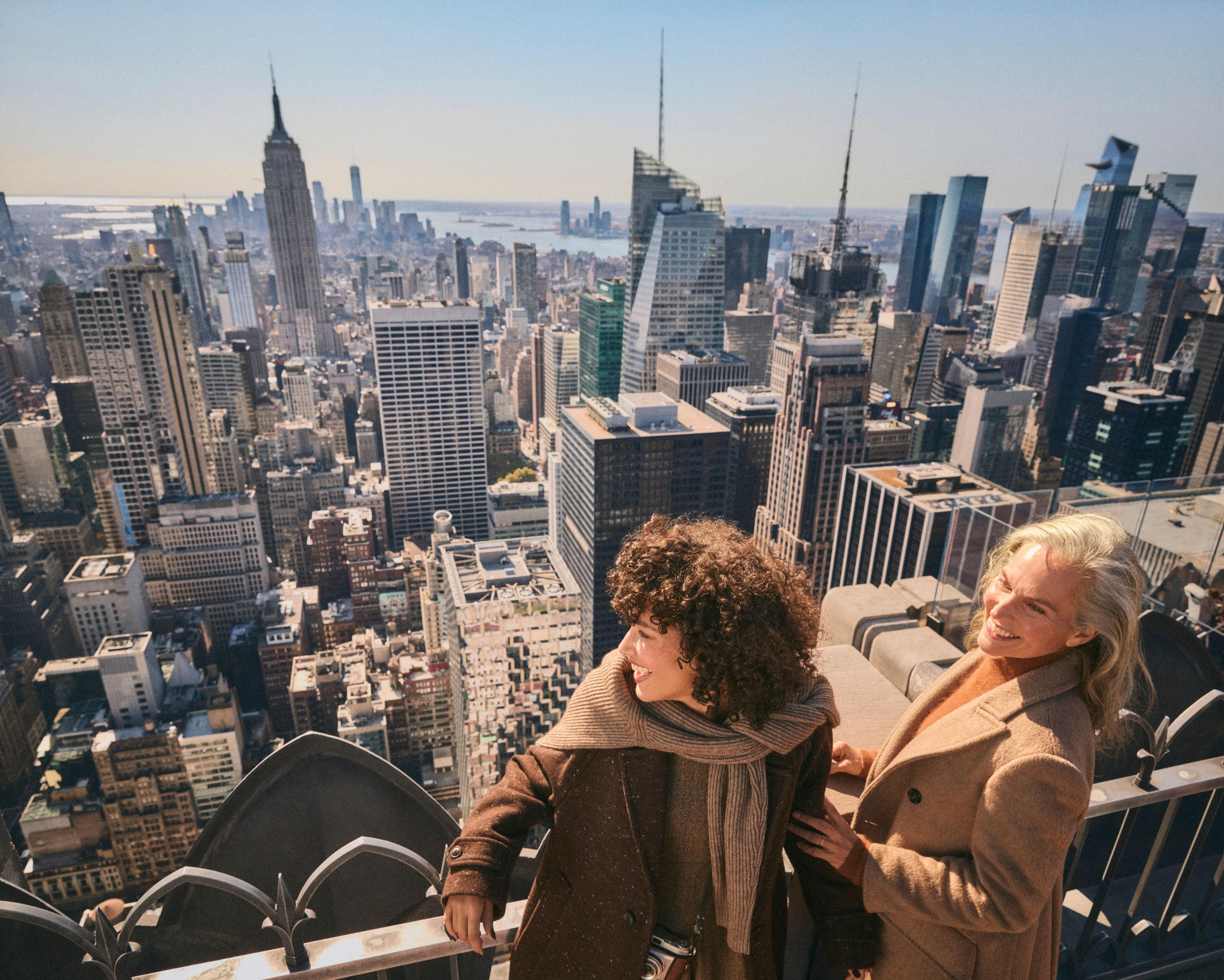 two women smiling at top of the rock