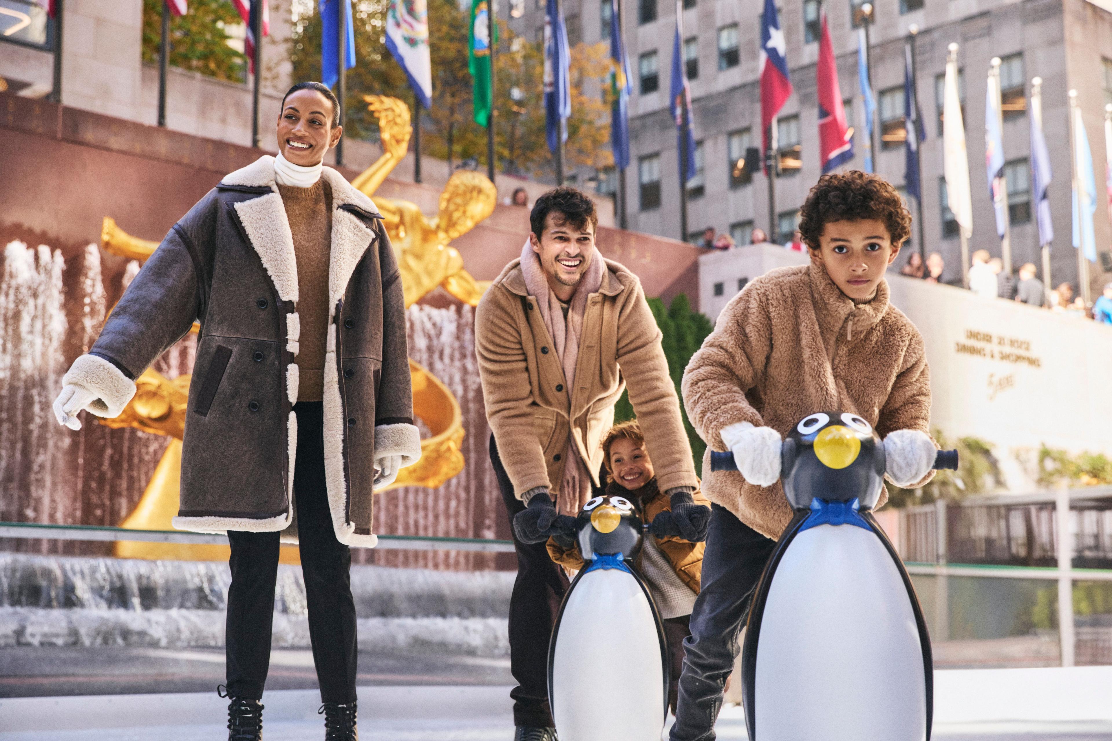 A mother and two children ice skating at The Rink at Rockefeller Center