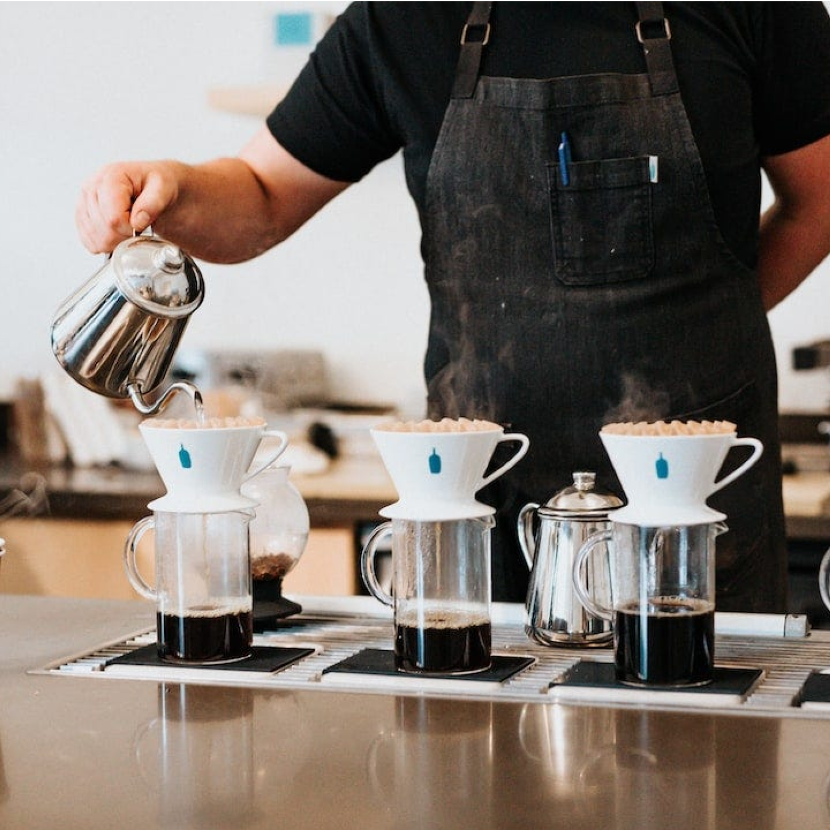 Person pouring coffee in mugs at Blue Bottle Coffee at Rockefeller Center