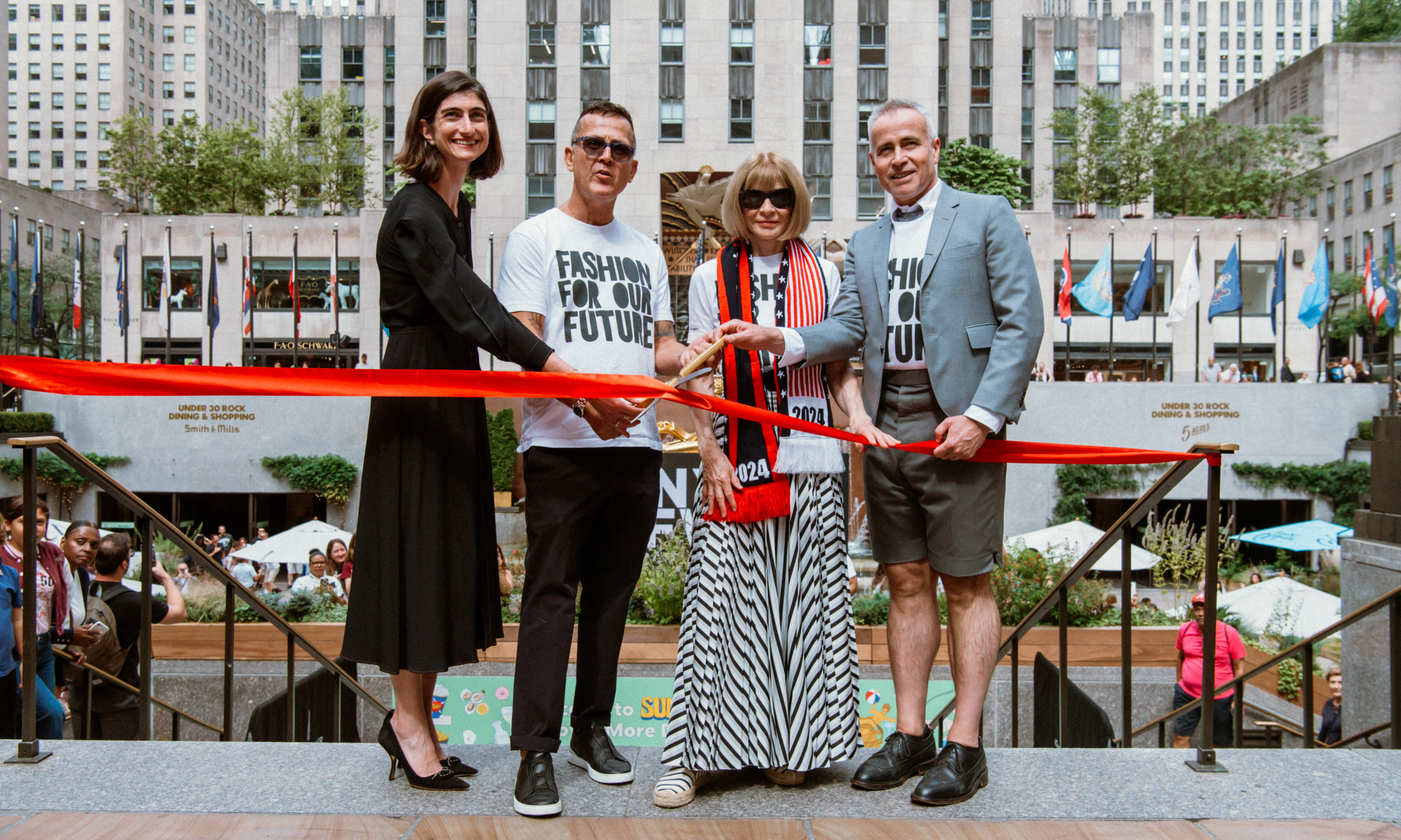 Four people cutting a red ribbon at Rockefeller Center to mark the start of New York Fashion Week 2024