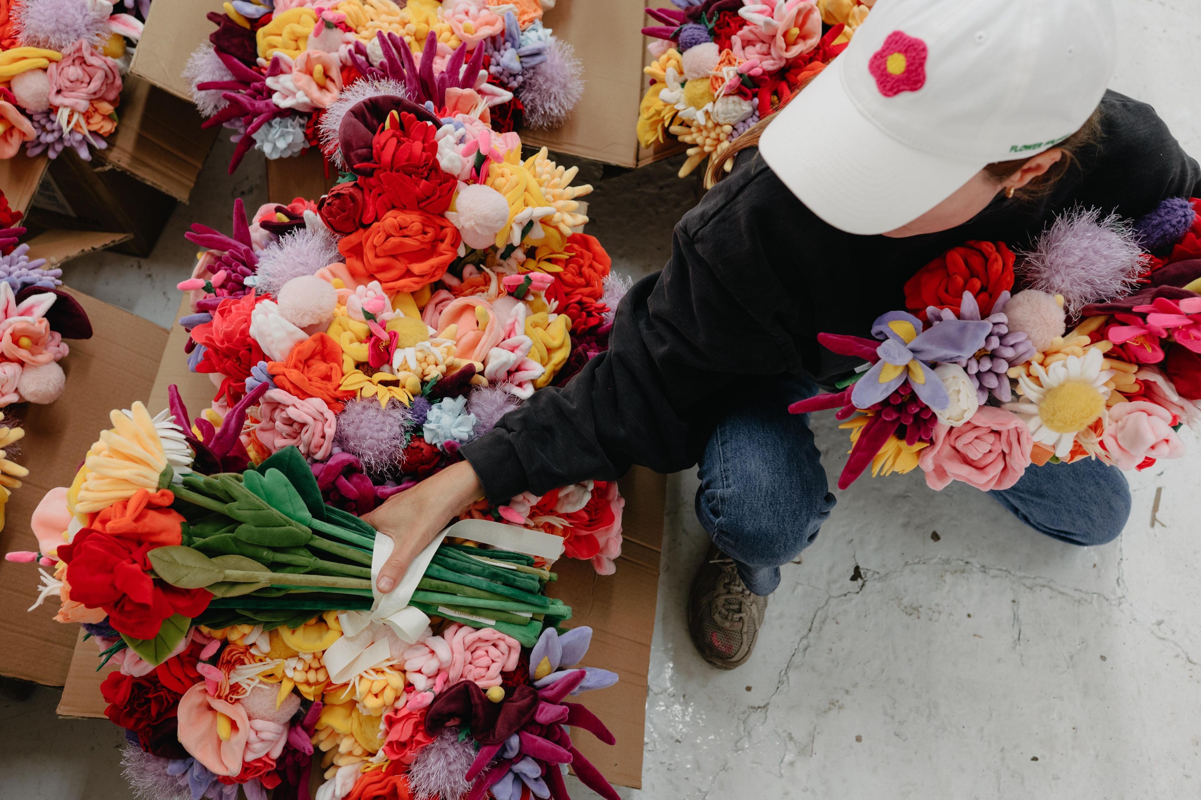 Overhead view of plush flowers being arranged in boxes