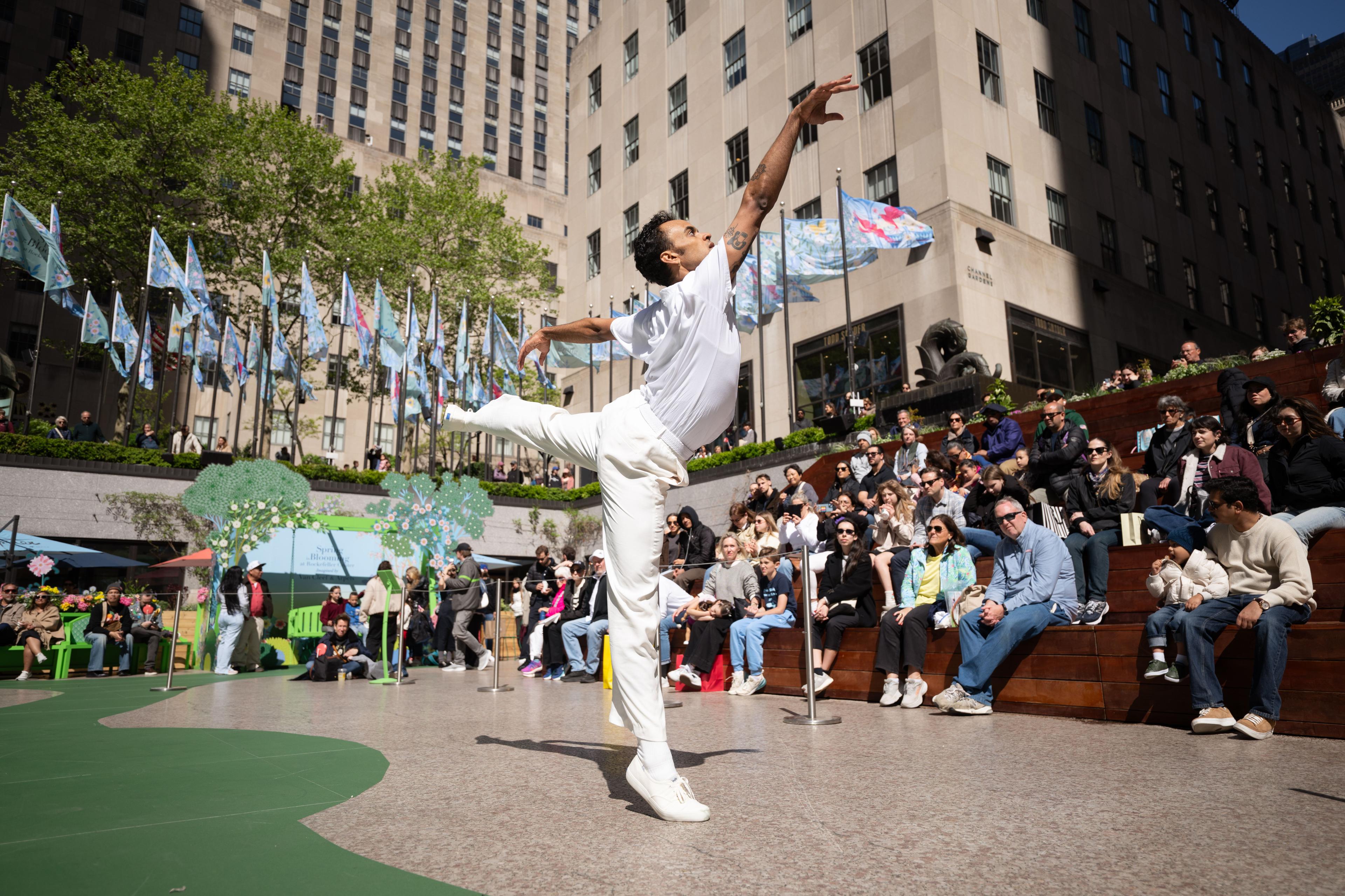 A dancer in all white doing contemporary dance during the Van Cleef & Arpels Spring is Blooming installation at Rockefeller Center