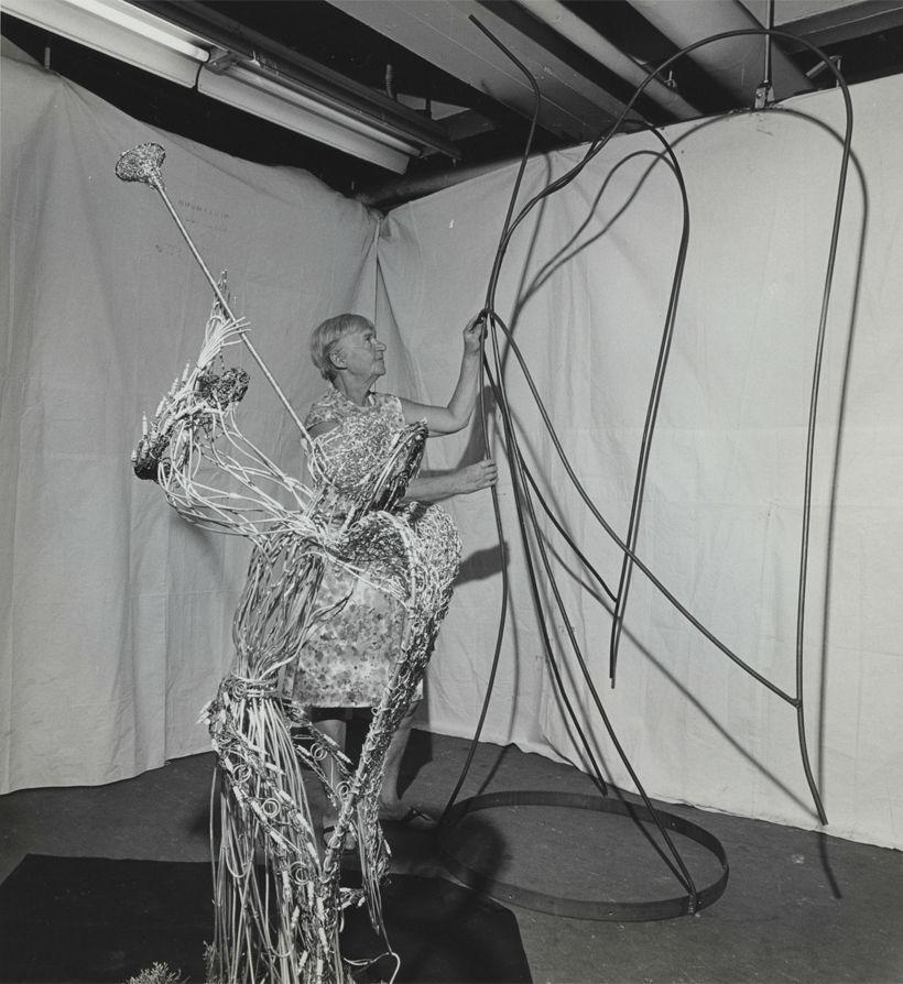 A black and white photo of an older woman tending to a clarebout angel.