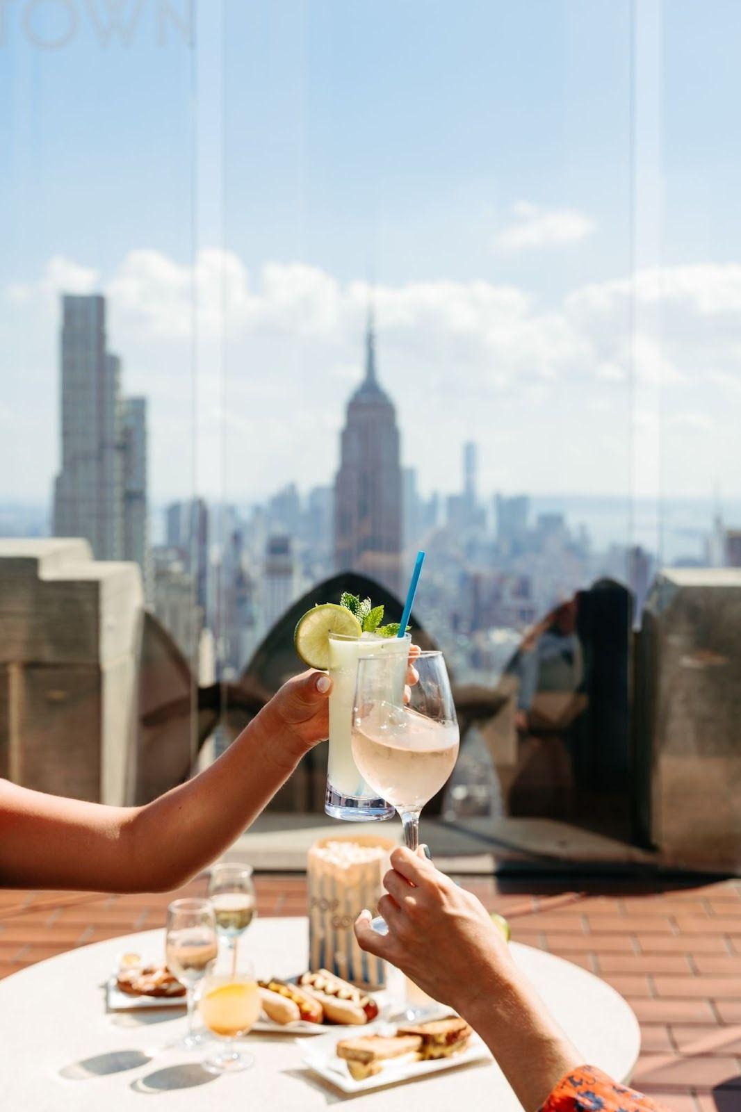 People holding drinks at a table with skyscrapers in the background