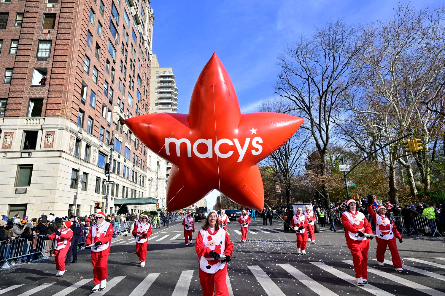 Group of people holding a large Macy's balloon during the Macy's Thanksgiving Day Parade