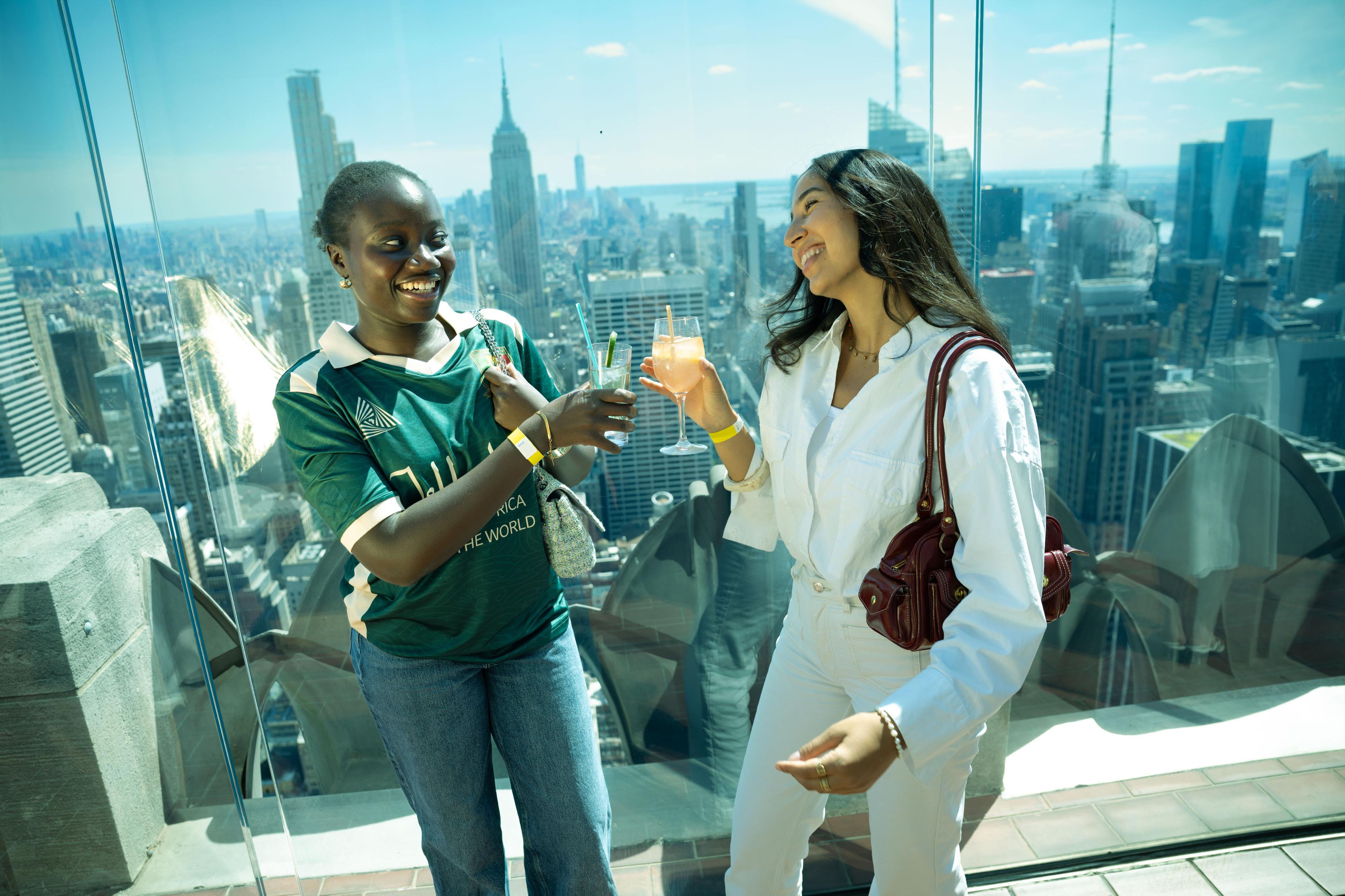 two fans cheersing drinks at top of the rock
