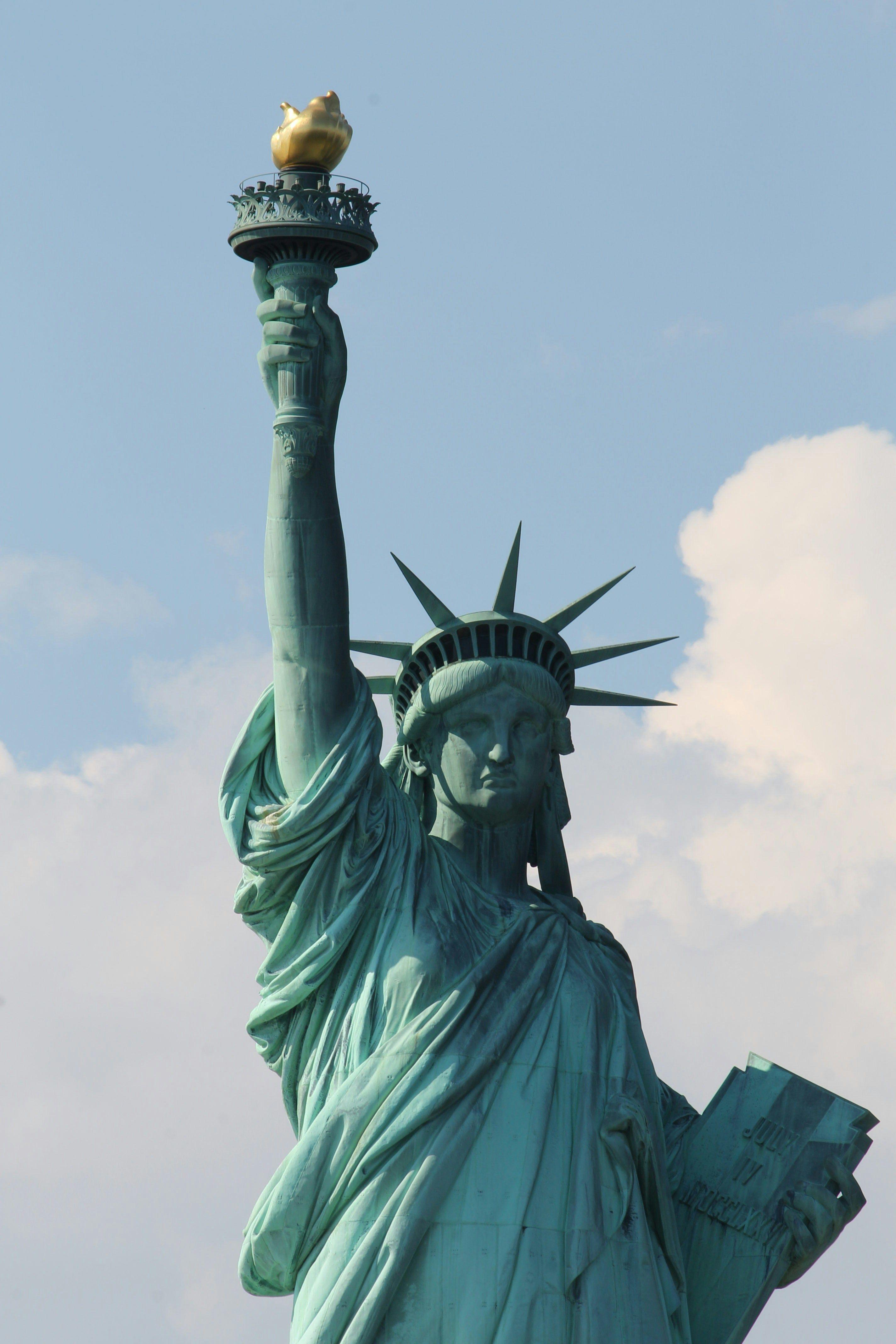 The Statue of Liberty against a partly cloudy sky.