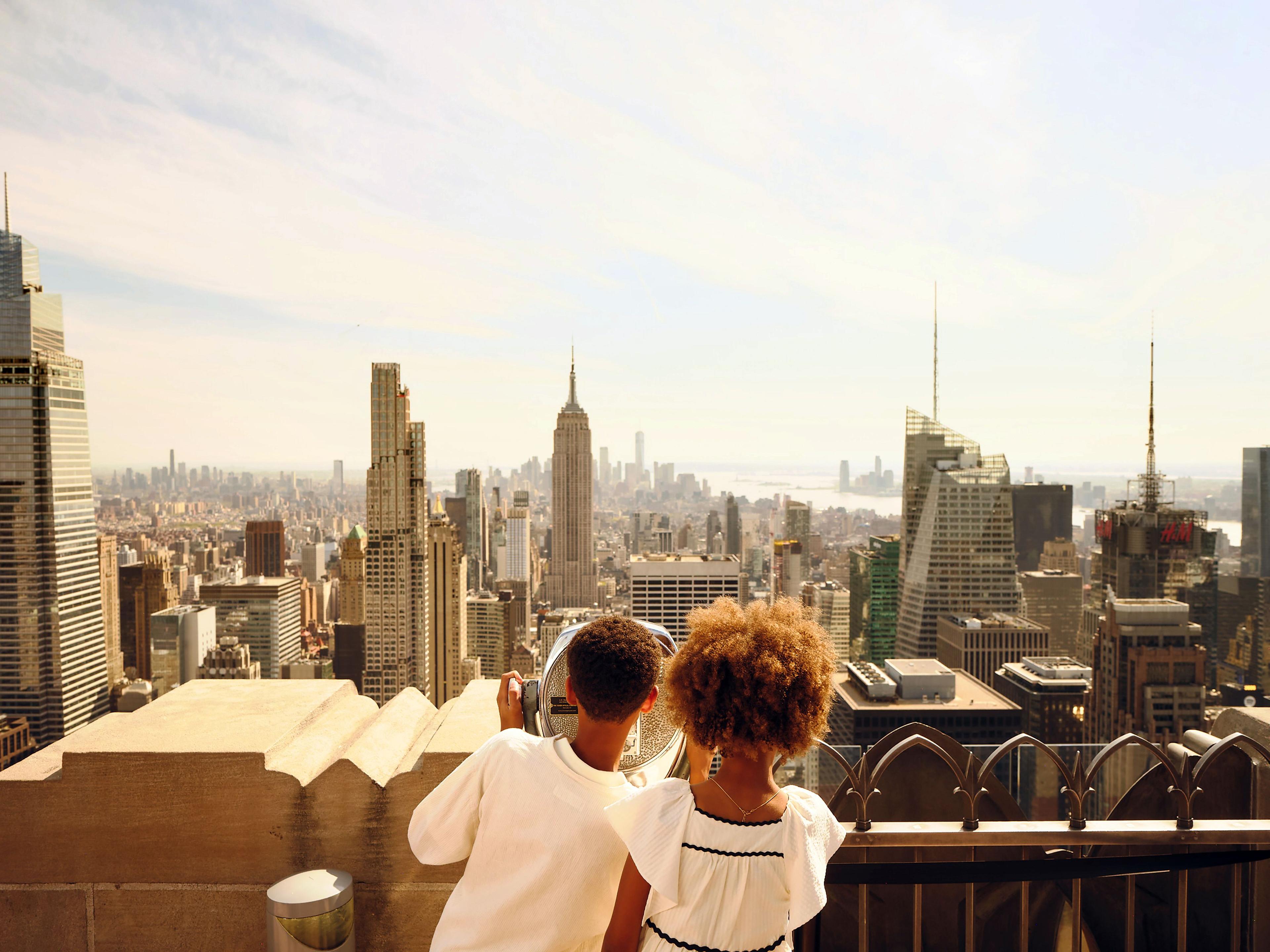 two kids looking out at the view of new york city from top of the rock