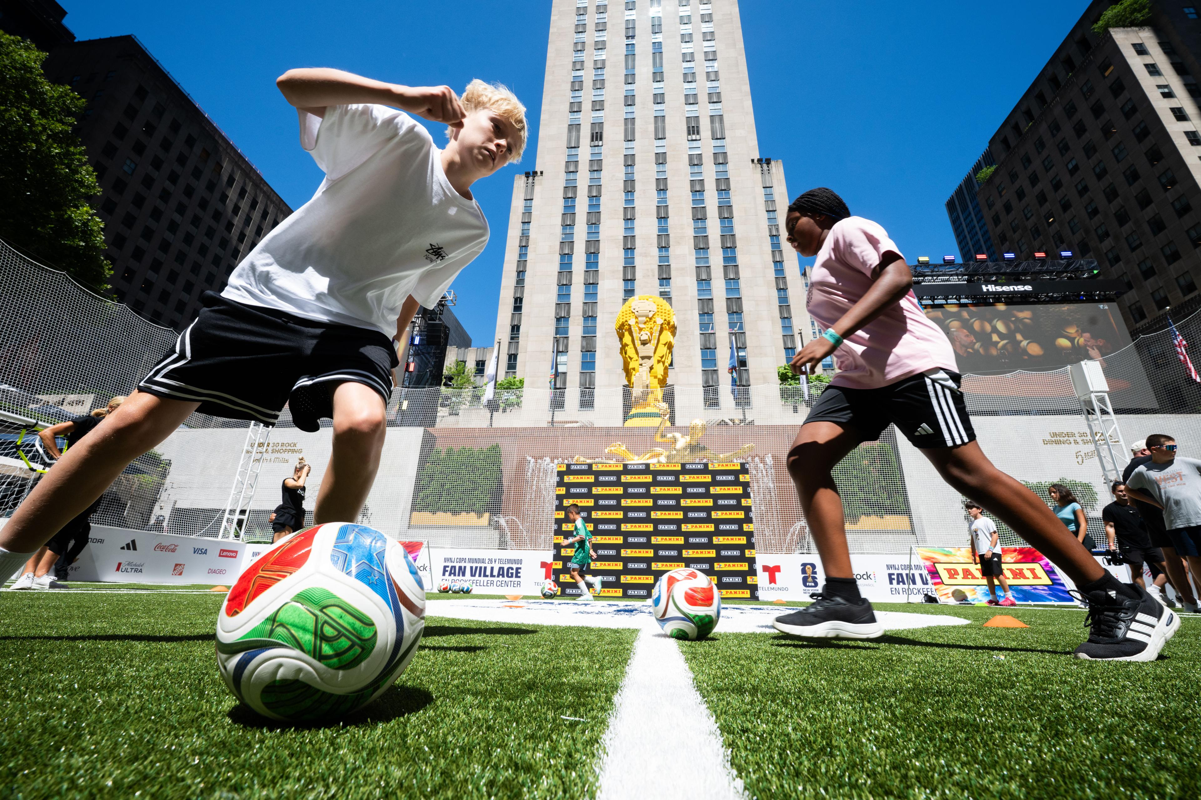 two kids playing soccer at rockefeller center
