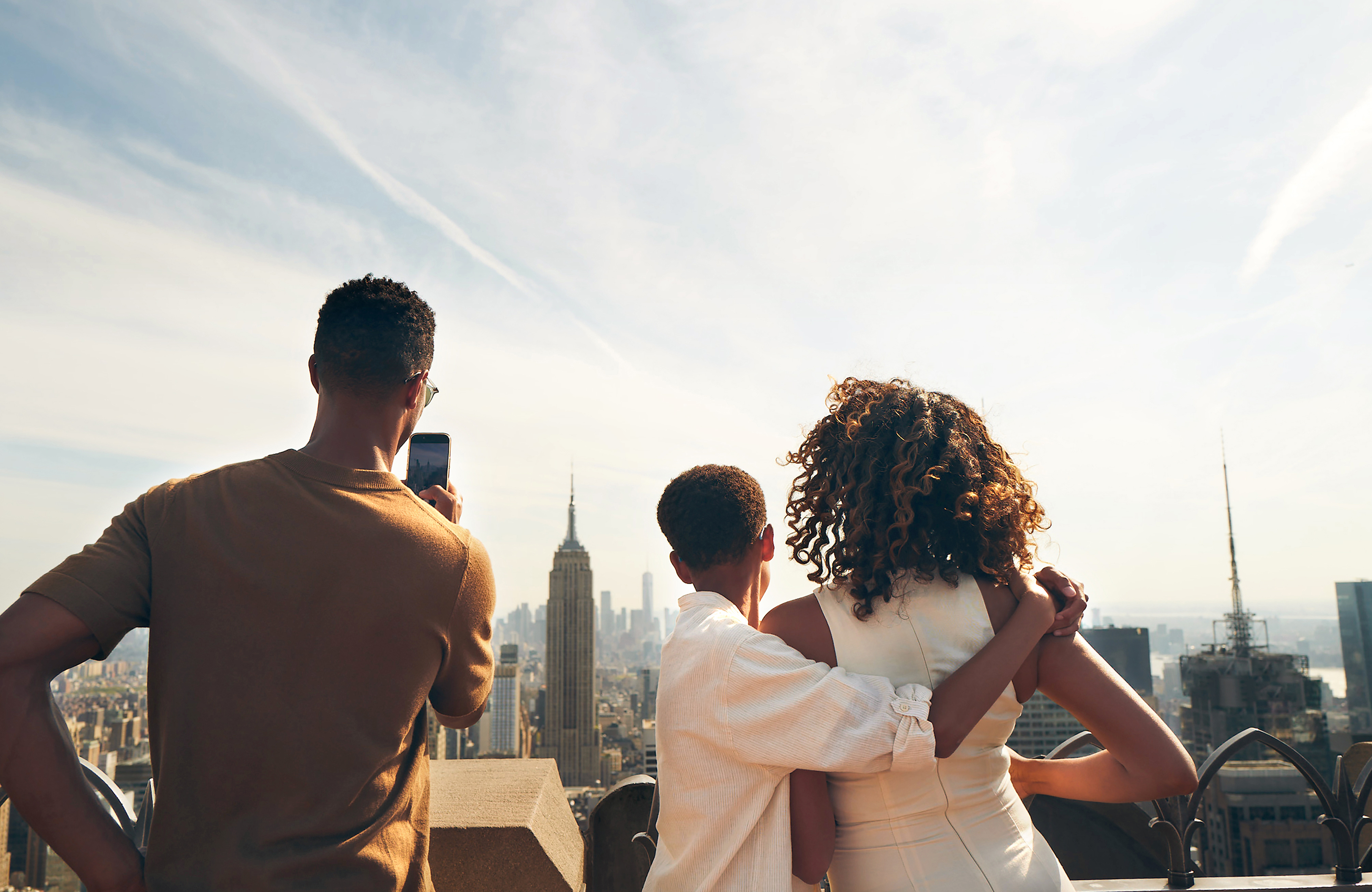 A family enjoying the view from Top of the Rock, with the Empire State Building in the distance