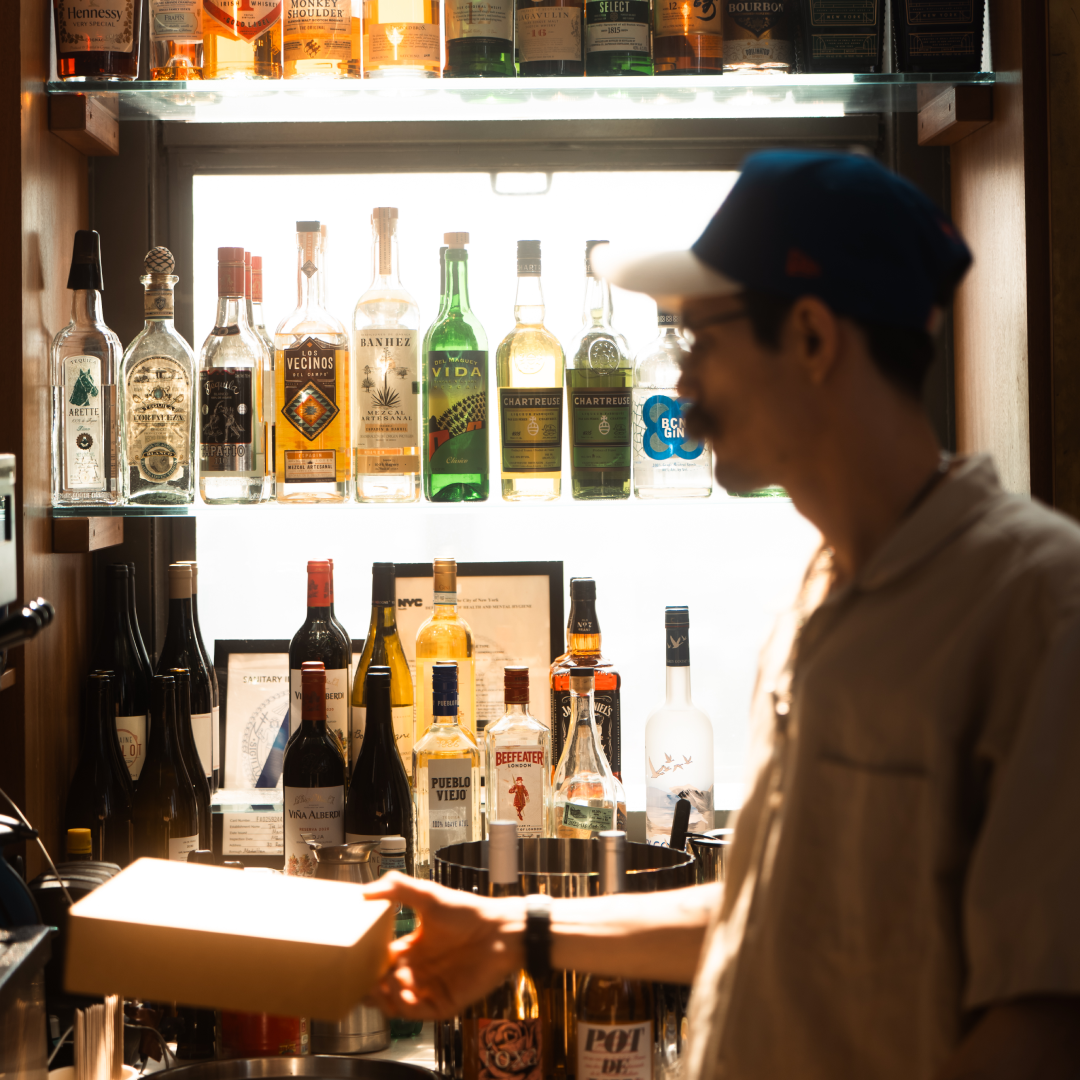 A Weather Room bartender standing in front a display of liquor