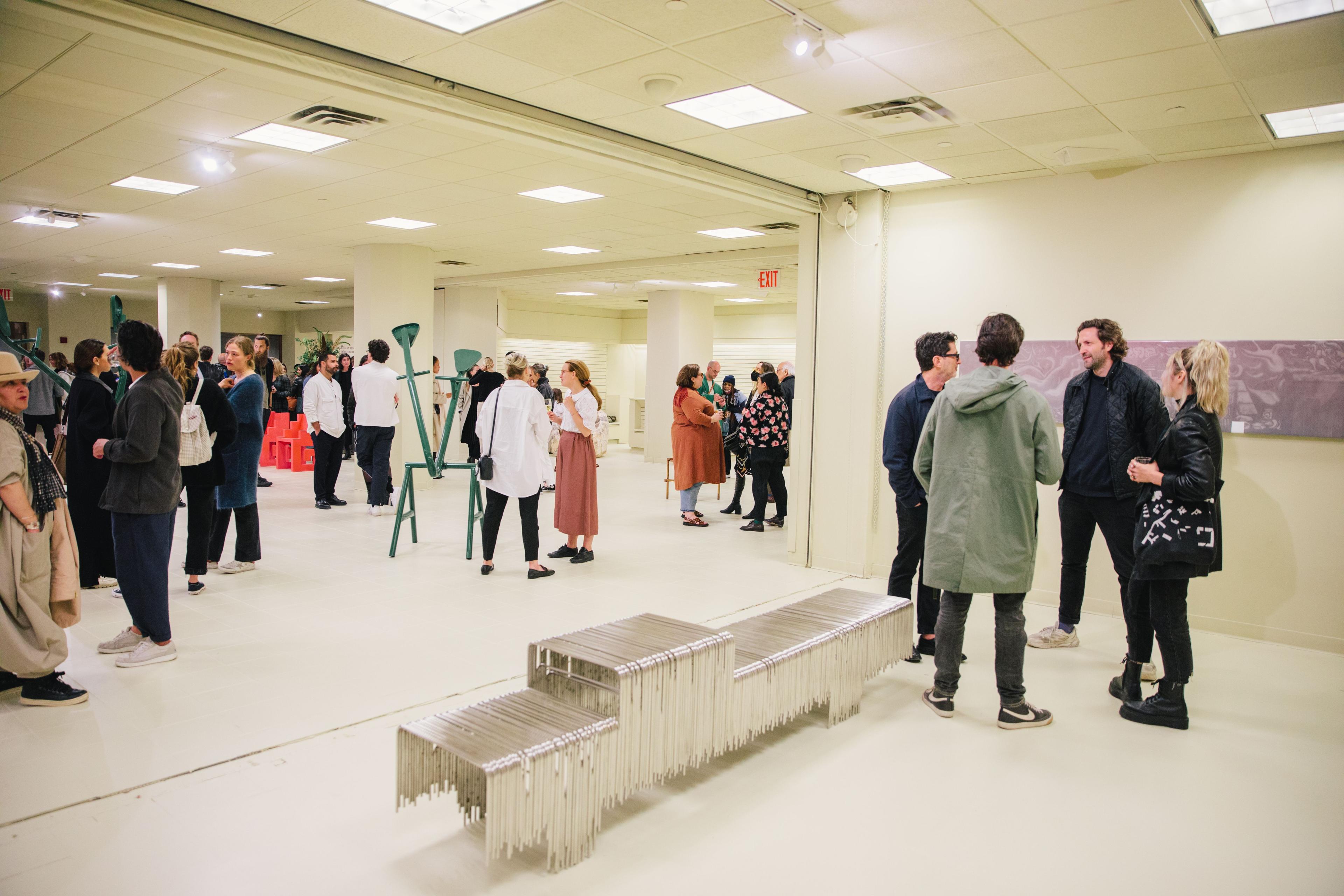 People standing next to a silver bench featured in MASA's exhibition at Rockefeller Center