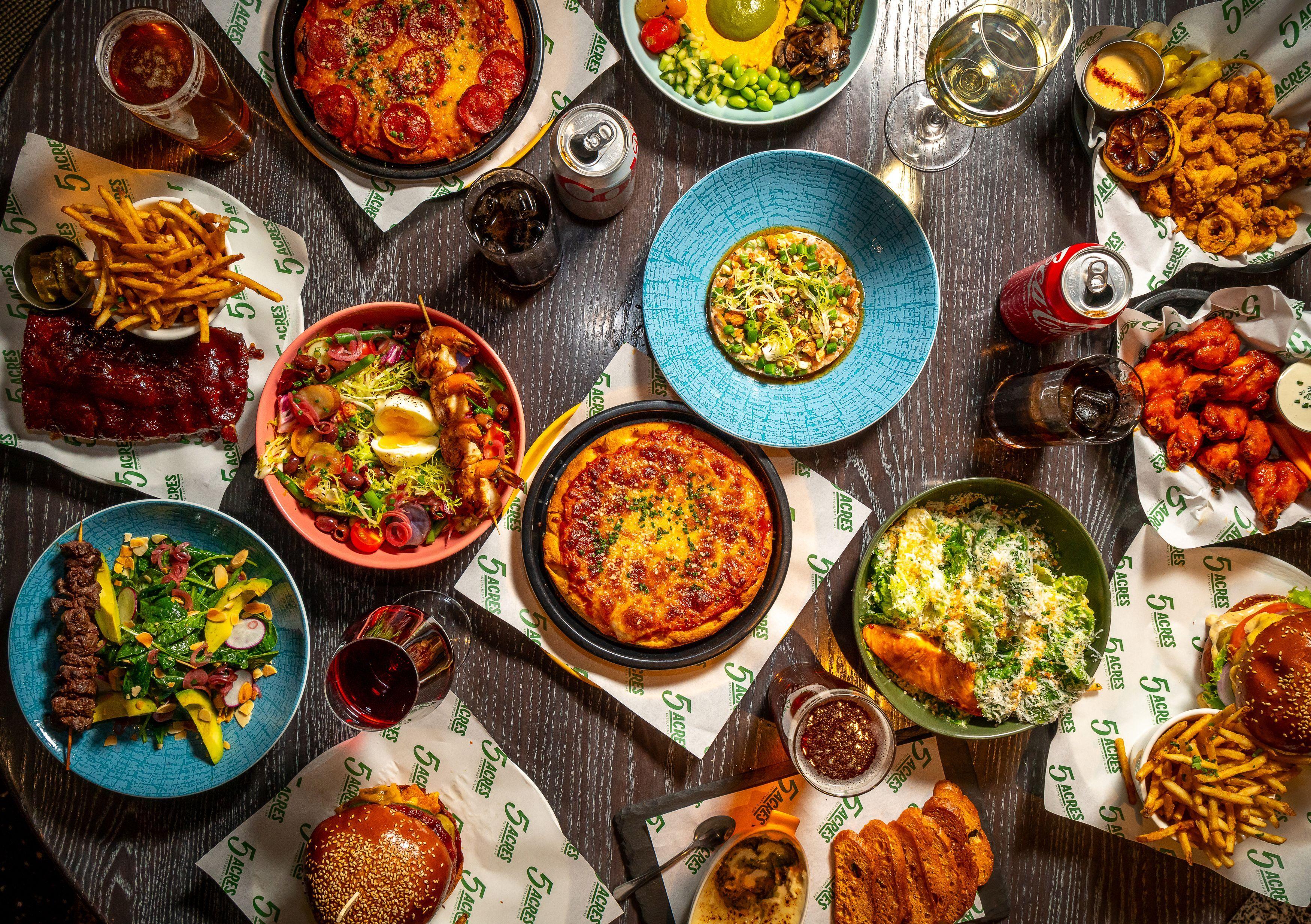 A spread of various brightly colored plates of food at 5 Acres Restaurant