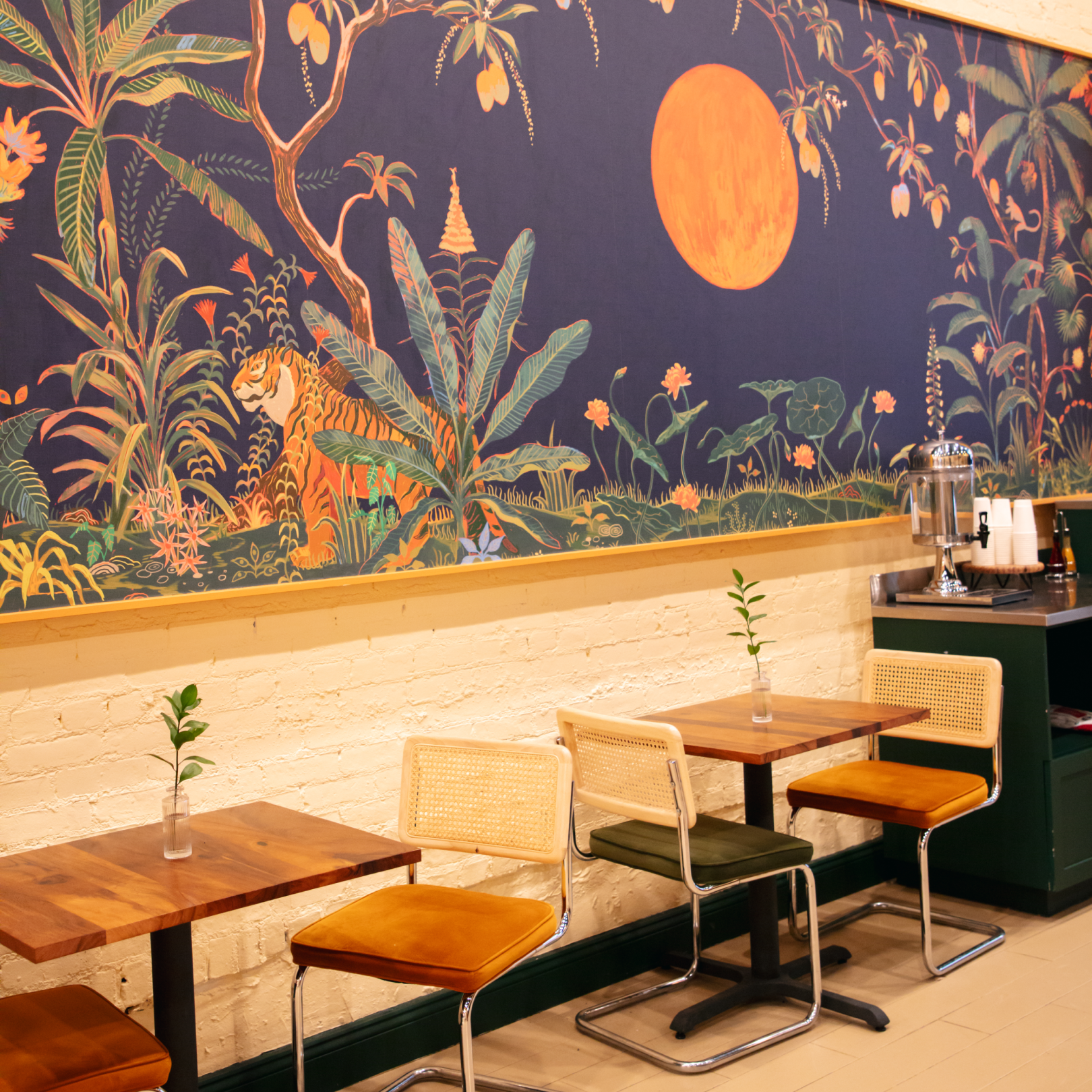 Tables and chairs under a colorful mural at Inday
