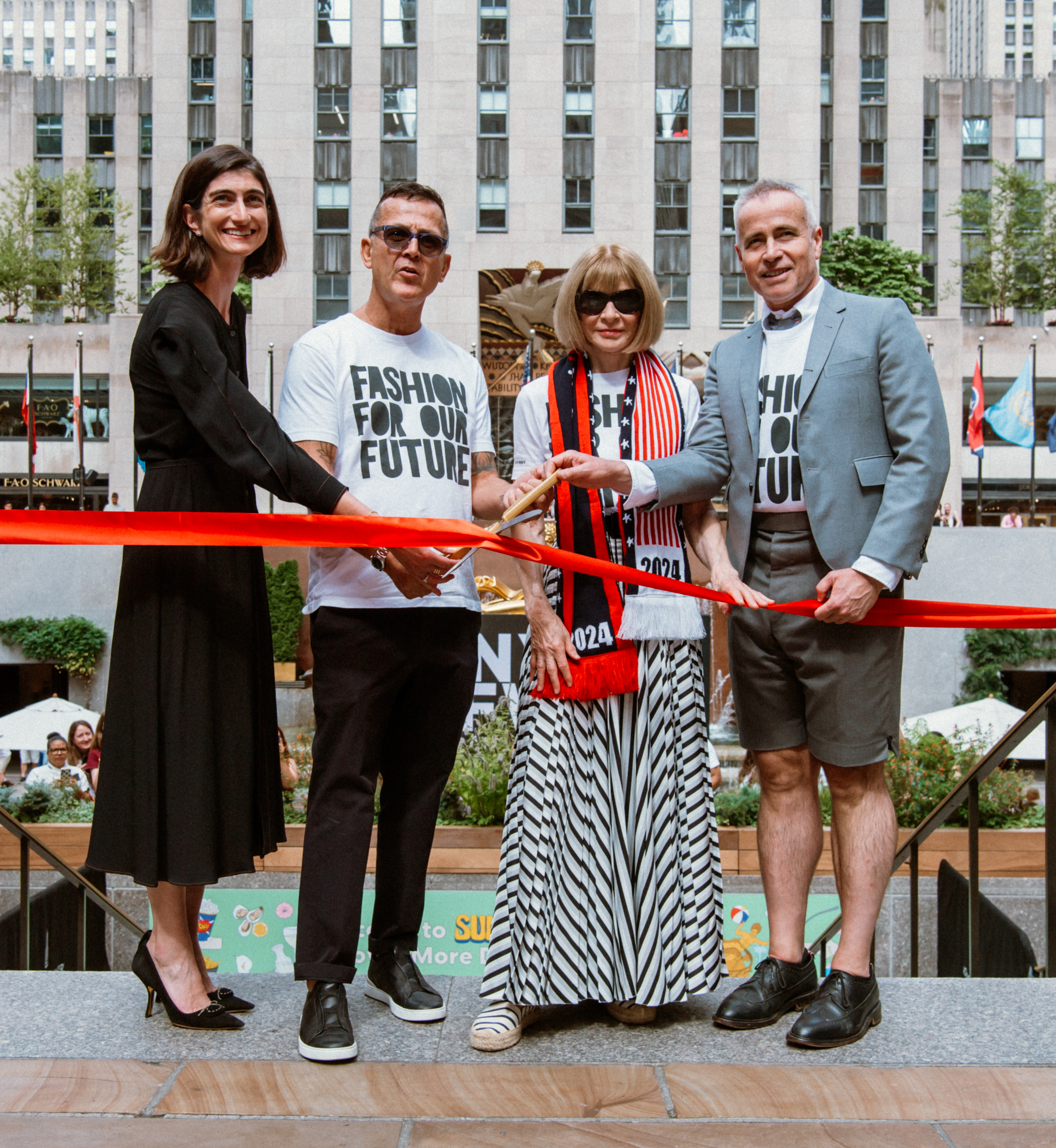 Four people cutting a red ribbon to mark the start of New York Fashion Week at Rockefeller Center