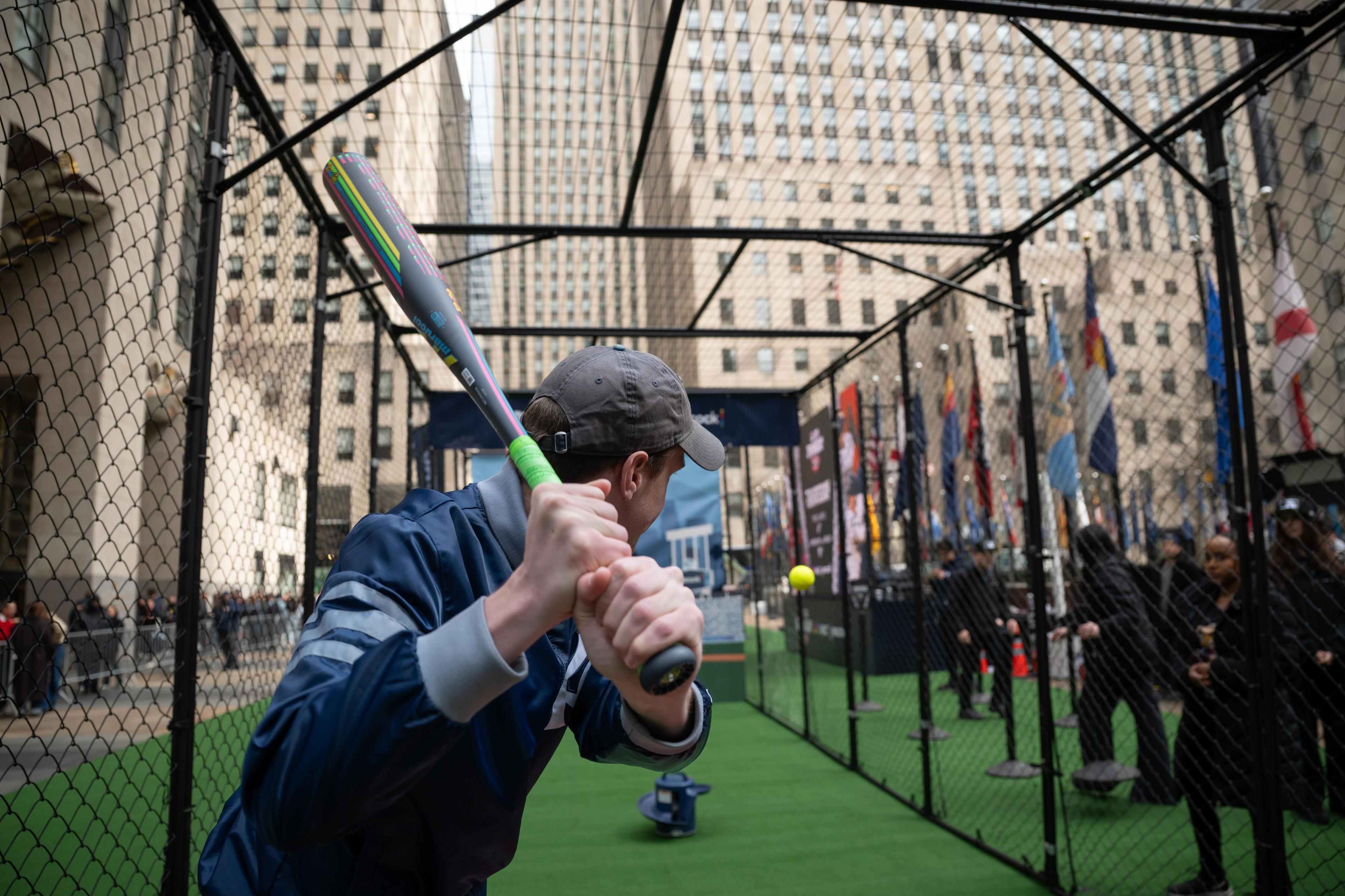man playing baseball at rockefeller center