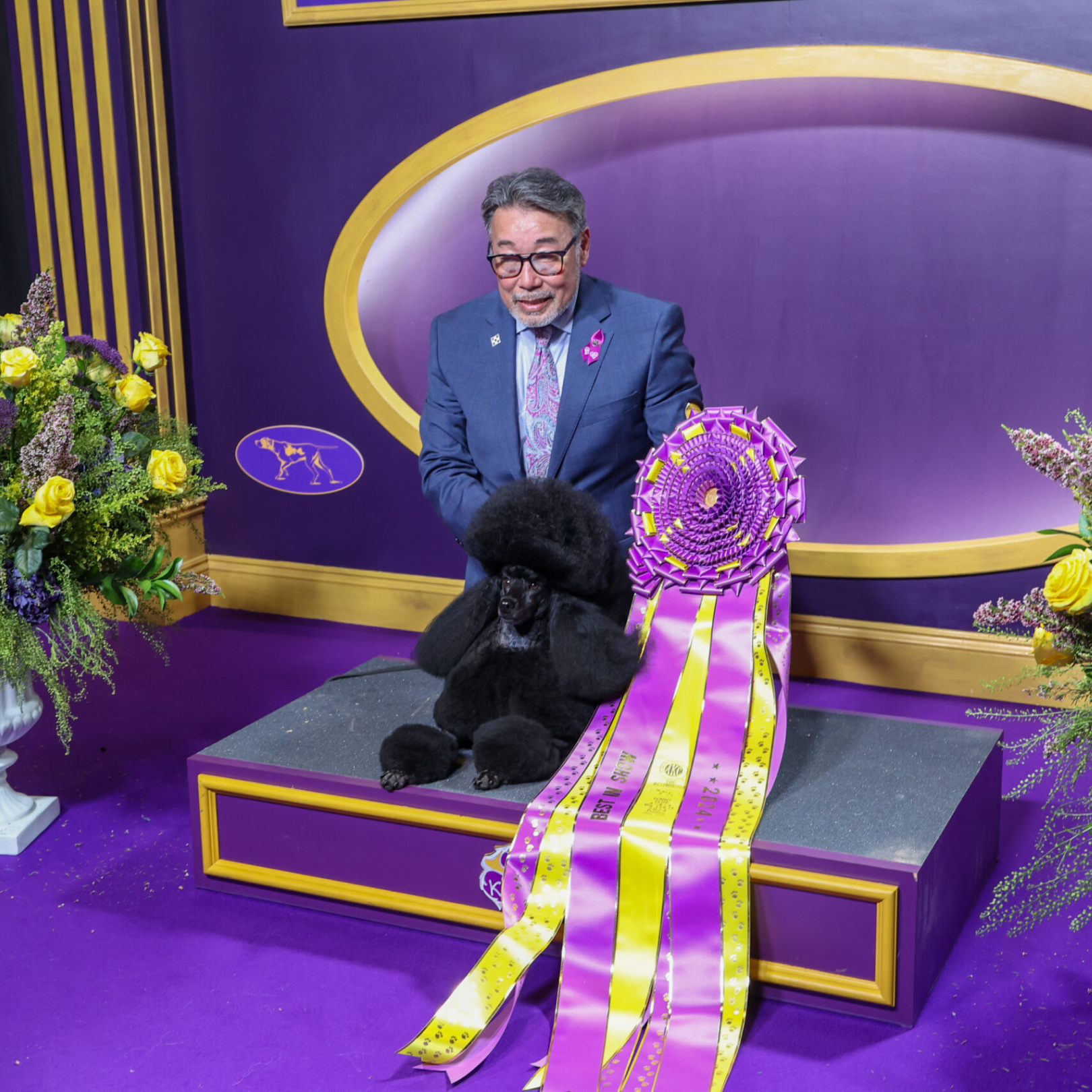 A dog and its handler posing for photos after winning "Best in Show" at the Westminster Kennel Club Dog Show