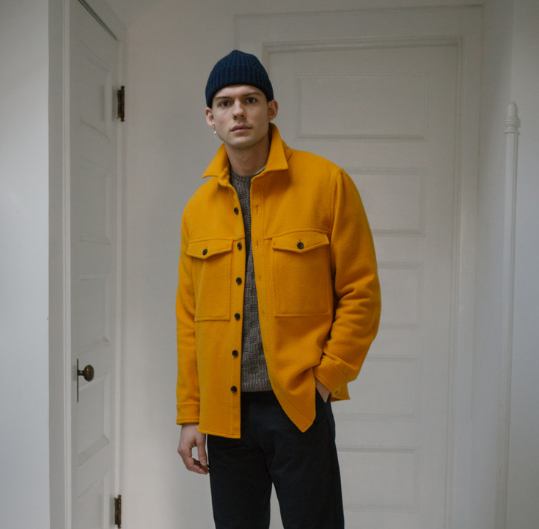 Image of a model from Steven Alan wearing a grey sweater and yellow jacket