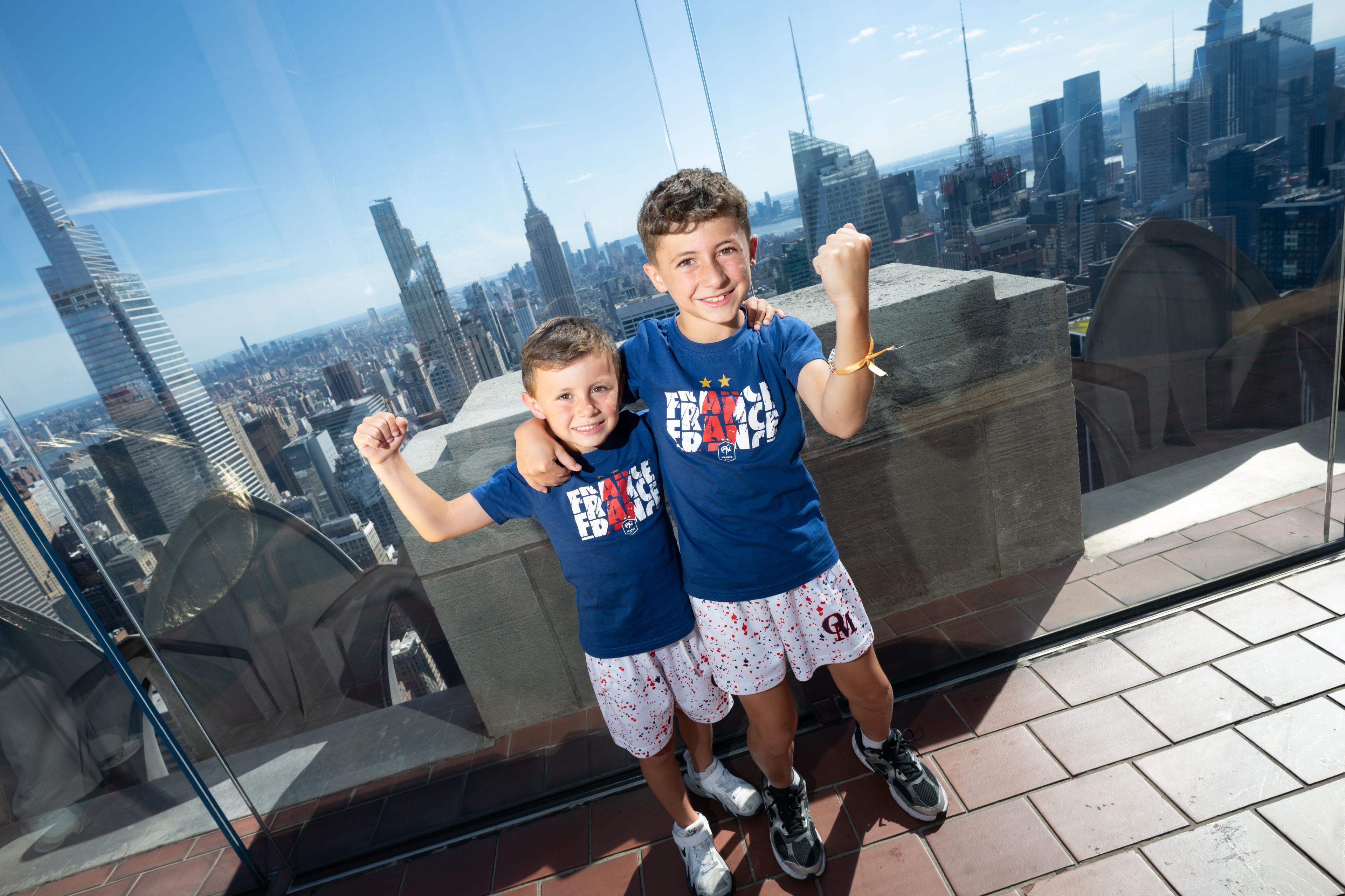 two kids smiling in soccer jerseys at top of the rock