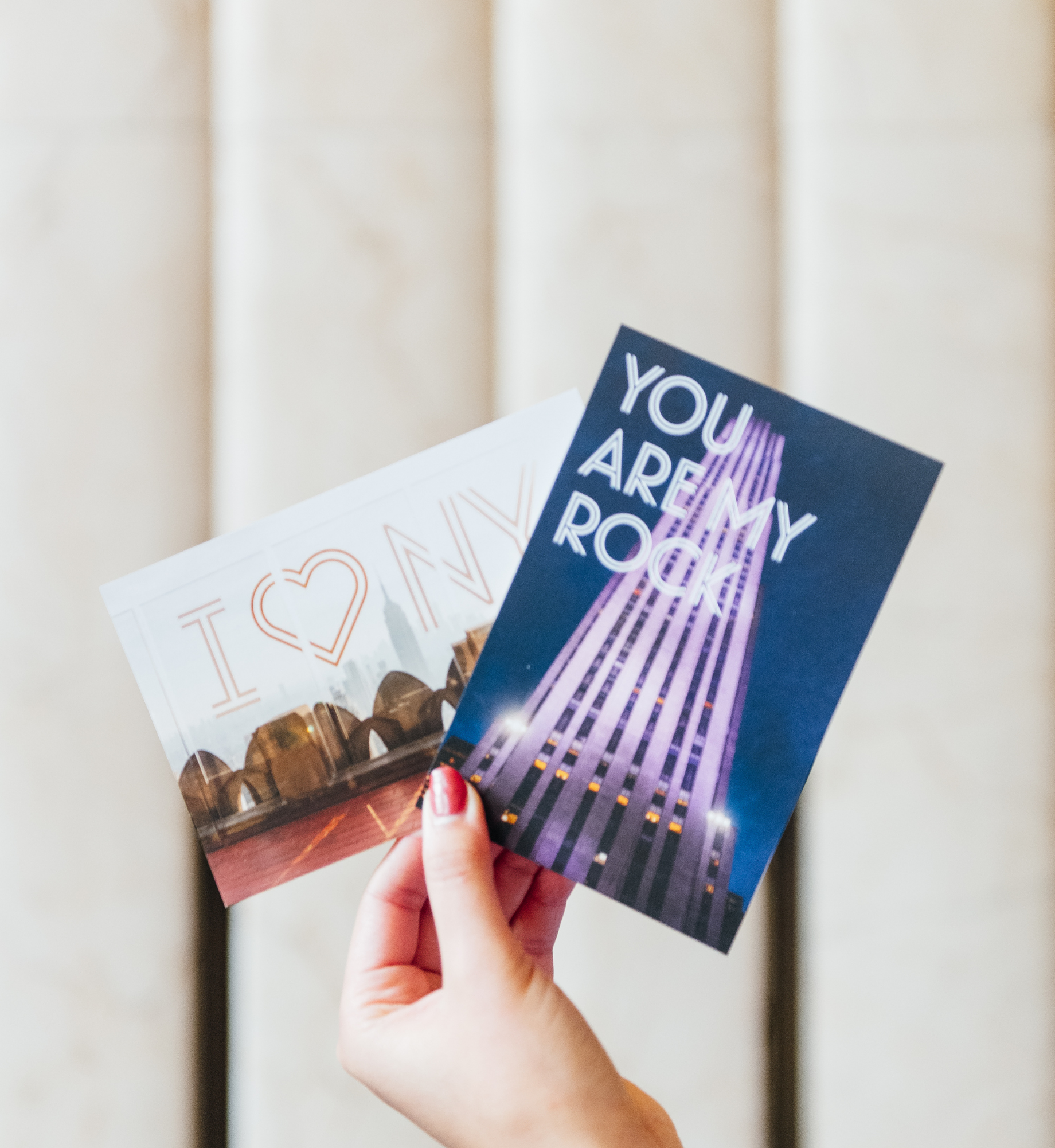 Woman holding up two Rockefeller Center postcards